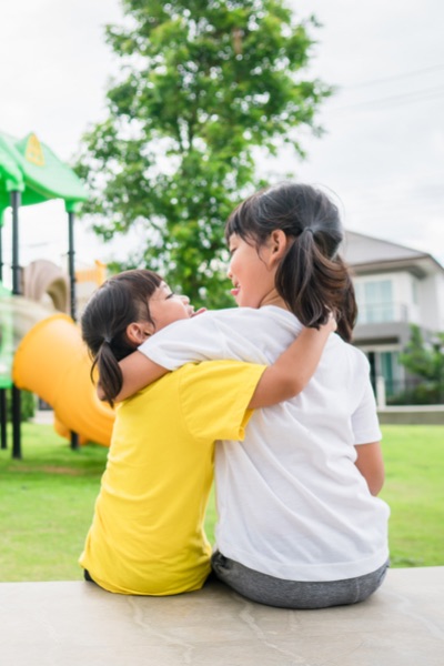 Kind sister hugging her younger sister