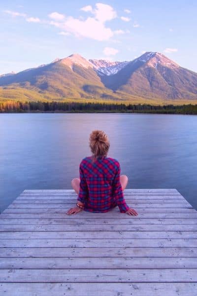A Mom calming down by the age of the river looking over a mountain. A calm scene