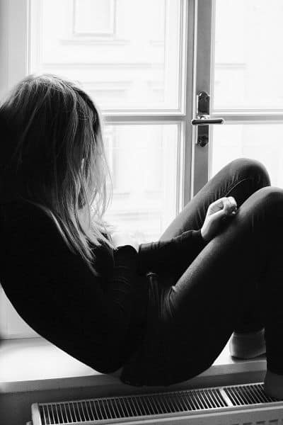 A teen girl sitting isolated by the window